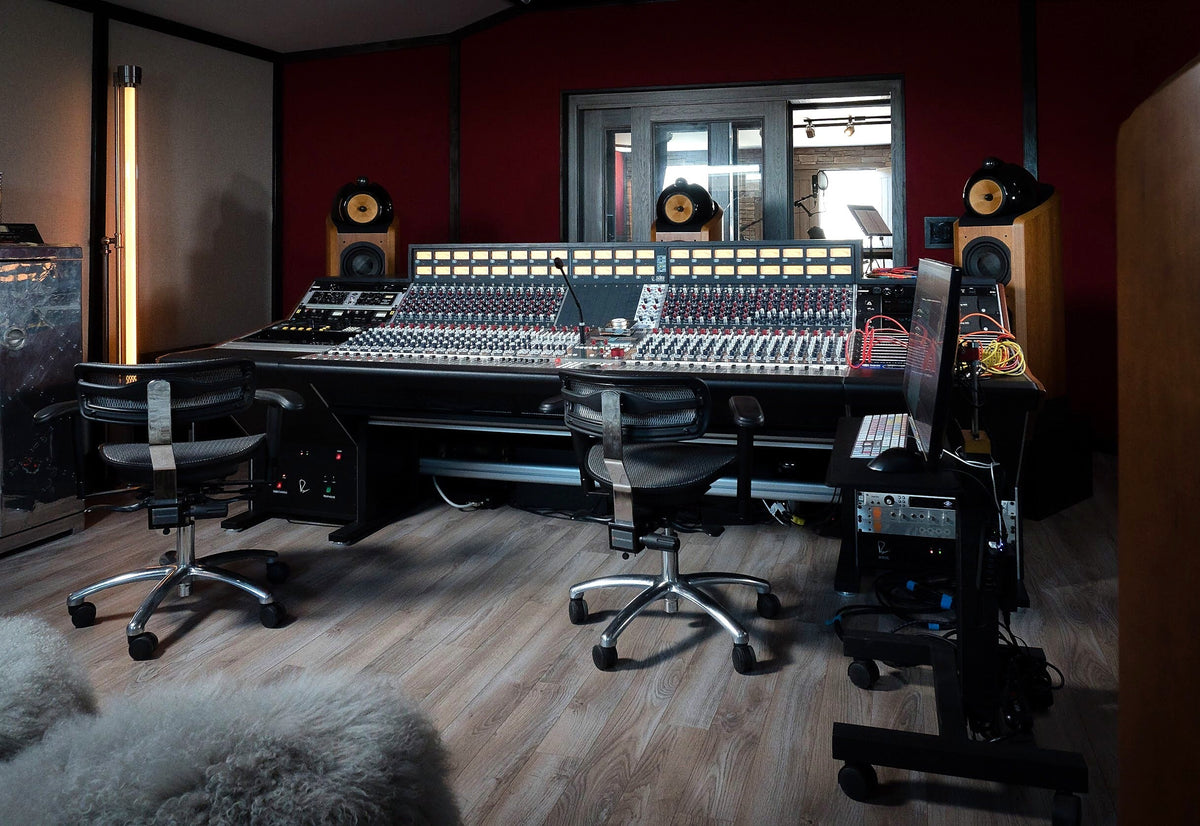 Recording studio with a large-format analog console, studio monitors and a window to the live room