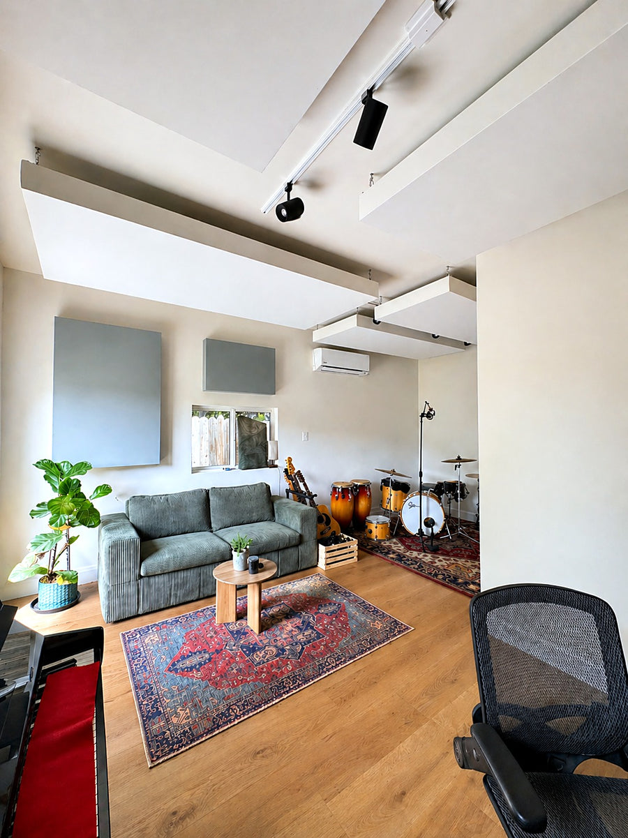 Live room with suspended ceiling clouds, gray fabric wall panels, a green sofa and a drum corner