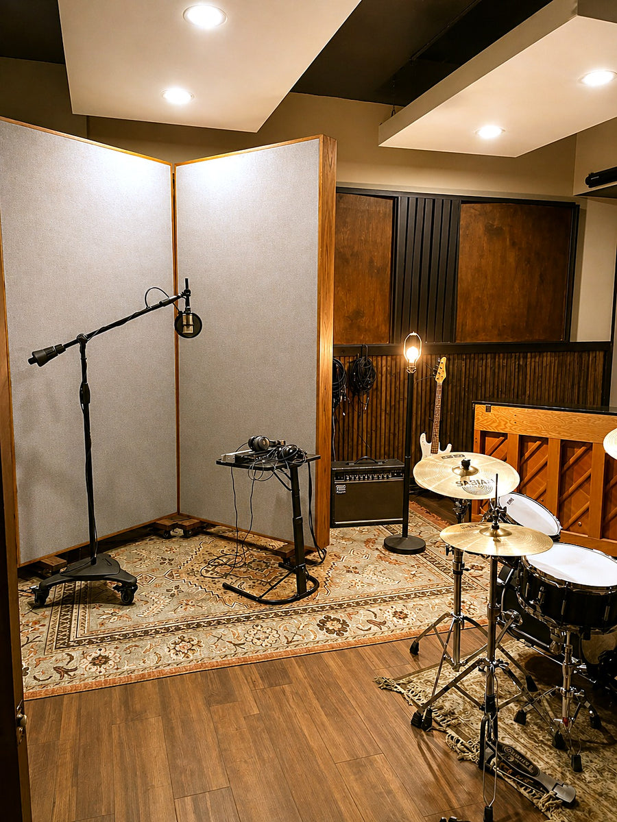 Tracking room with a two-panel wood-framed free-standing gobo beside a drum kit, suspended ceiling clouds and a wood slat wall